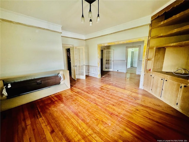 unfurnished living room with light hardwood / wood-style floors, french doors, and crown molding