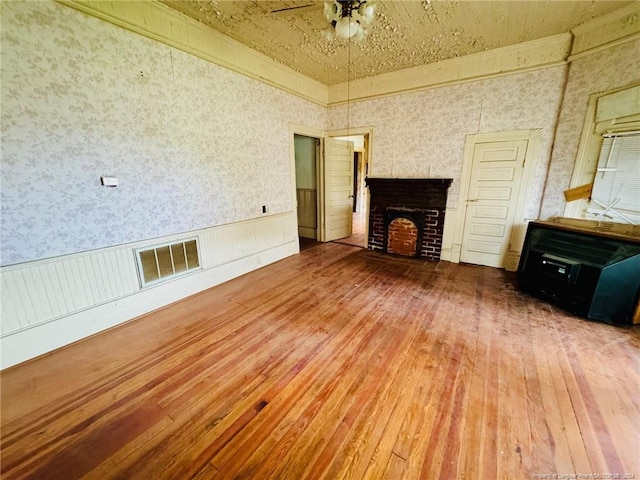 unfurnished living room with wood-type flooring, a fireplace, and ceiling fan