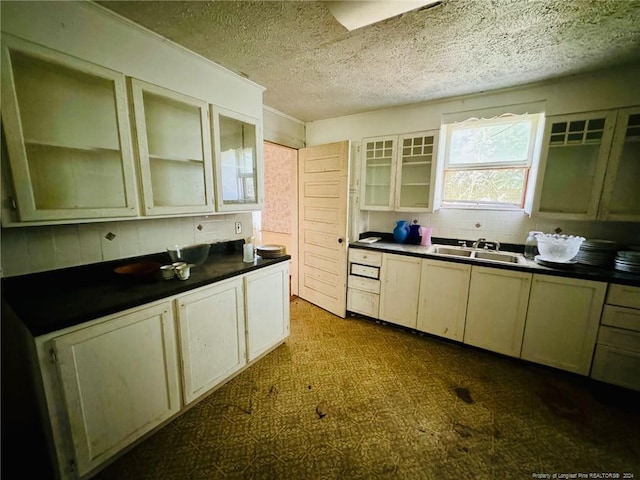 kitchen with a textured ceiling, cream cabinetry, and sink