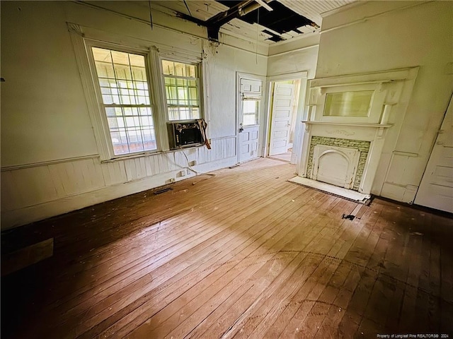 unfurnished living room with wood-type flooring, cooling unit, and wooden walls