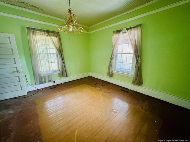 unfurnished room with wood-type flooring, ornamental molding, and an inviting chandelier