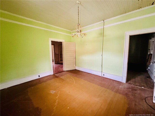 spare room featuring a notable chandelier, crown molding, and hardwood / wood-style flooring