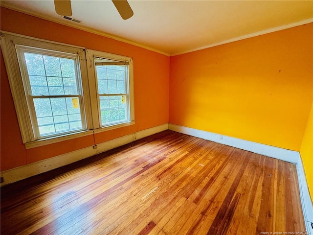 empty room featuring ornamental molding, wood-type flooring, and ceiling fan