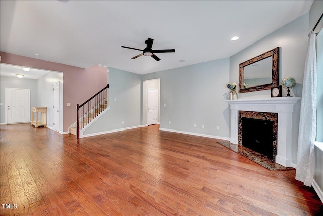 unfurnished living room with wood-type flooring, ceiling fan, and a premium fireplace