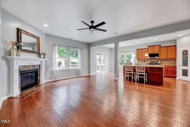 living room featuring a wealth of natural light, light hardwood / wood-style floors, a fireplace, and ceiling fan