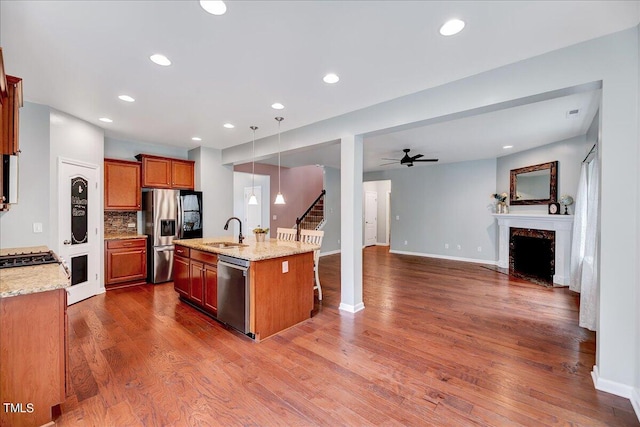 kitchen with appliances with stainless steel finishes, dark hardwood / wood-style flooring, decorative light fixtures, a center island with sink, and sink