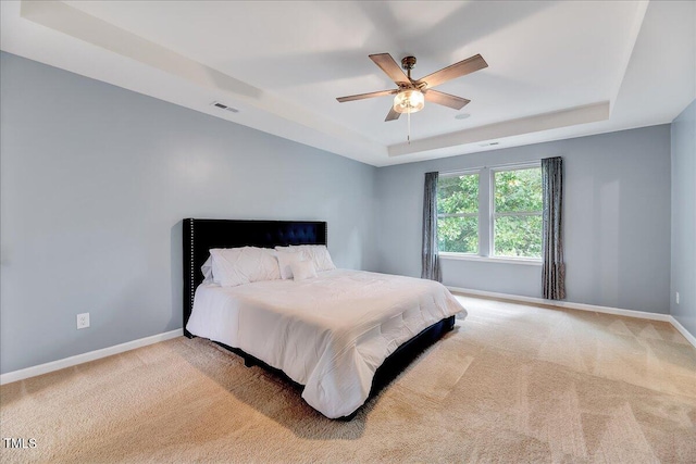 carpeted bedroom featuring a tray ceiling and ceiling fan