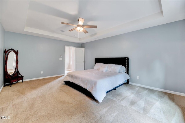 carpeted bedroom featuring a tray ceiling and ceiling fan