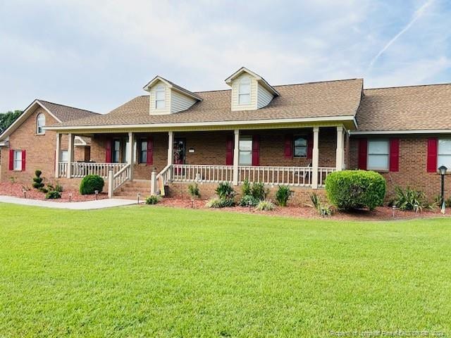 view of front of property with brick siding, a front lawn, and a porch