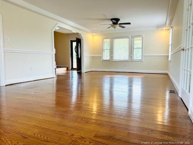spare room featuring ceiling fan, wood finished floors, baseboards, and arched walkways