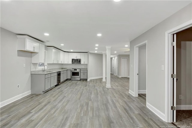 kitchen featuring sink, white cabinetry, stainless steel appliances, tasteful backsplash, and light stone countertops