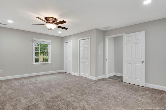 unfurnished bedroom featuring light carpet, two closets, and ceiling fan