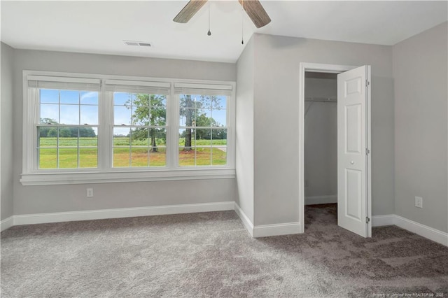 unfurnished bedroom featuring multiple windows, a walk in closet, and carpet