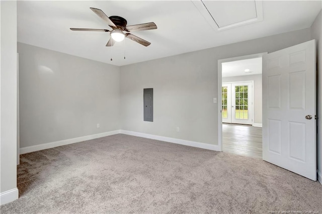 spare room with a ceiling fan, carpet, electric panel, and baseboards