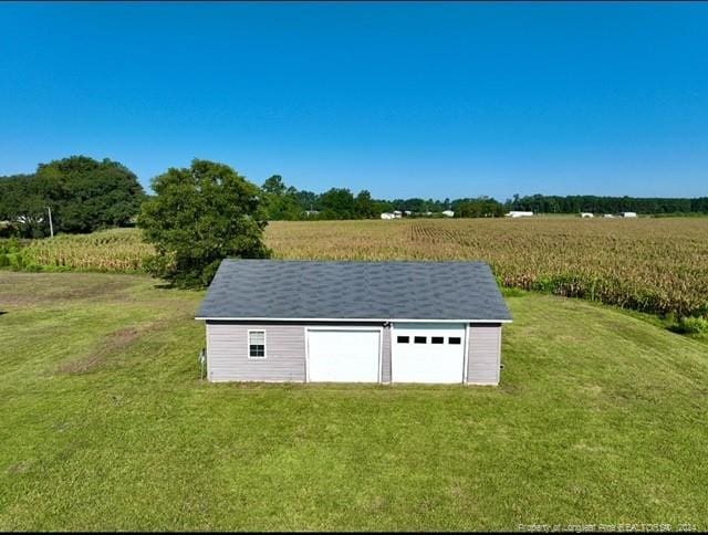 view of outdoor structure featuring a garage, a rural view, and a yard