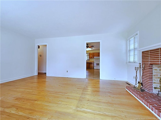 unfurnished living room with a brick fireplace, light hardwood / wood-style floors, and ceiling fan