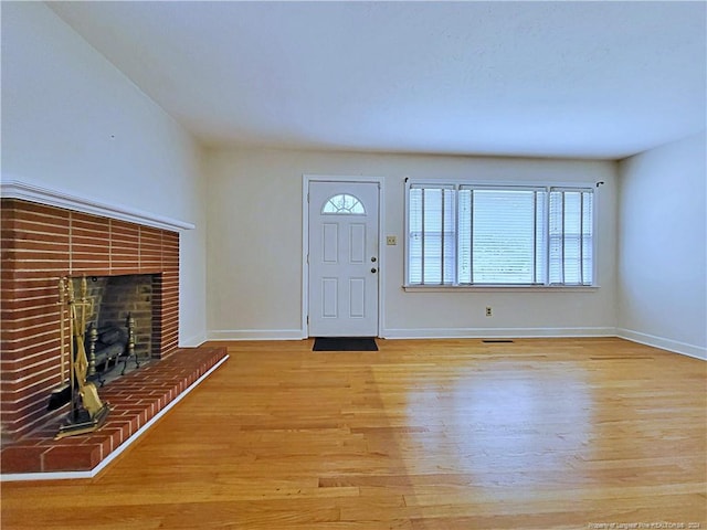 foyer entrance featuring light wood-type flooring and a fireplace