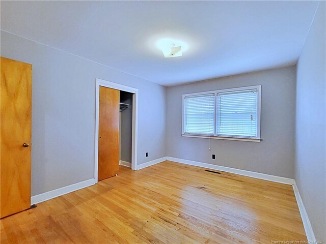 unfurnished bedroom with light wood-type flooring and a closet