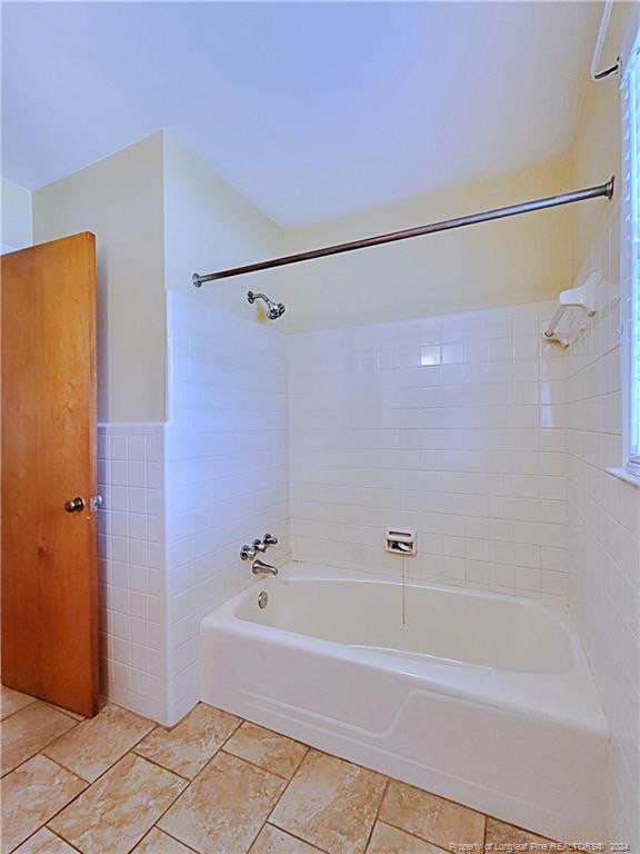 bathroom with tiled shower / bath and tile walls