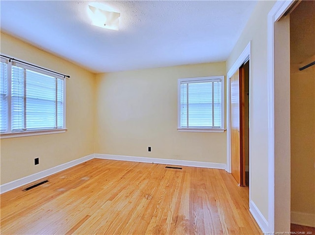 unfurnished bedroom featuring multiple windows, light hardwood / wood-style floors, and a closet