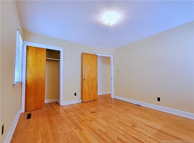 unfurnished bedroom with light wood-type flooring and a closet