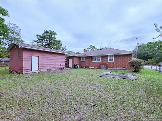 rear view of house featuring a patio, a yard, and a shed