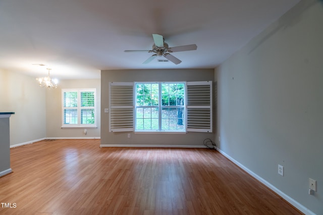 spare room featuring ceiling fan with notable chandelier and light hardwood / wood-style floors