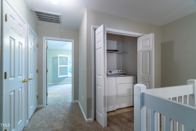 corridor with light colored carpet and separate washer and dryer