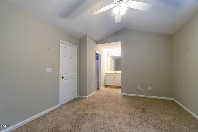 unfurnished bedroom with ceiling fan, ensuite bath, vaulted ceiling, and light carpet