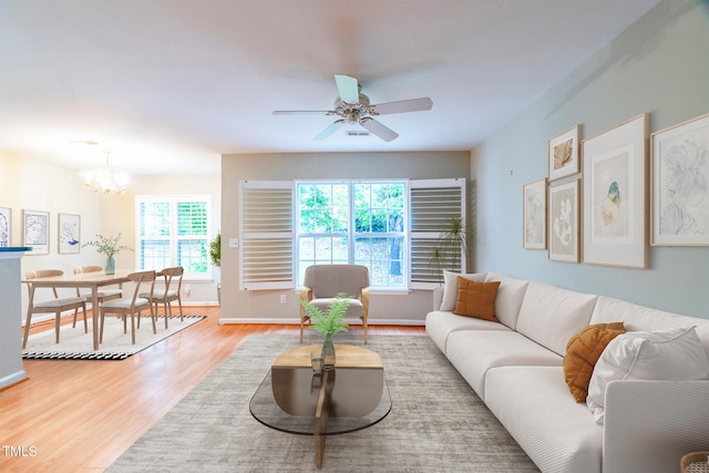 living room featuring ceiling fan with notable chandelier and hardwood / wood-style flooring