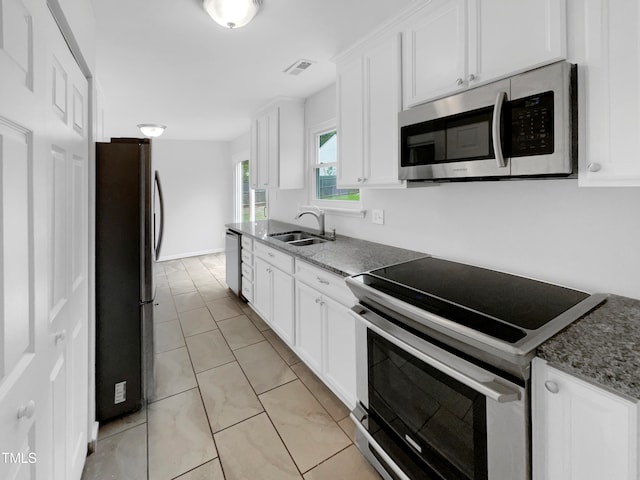 kitchen featuring dark stone counters, stainless steel appliances, white cabinetry, and sink