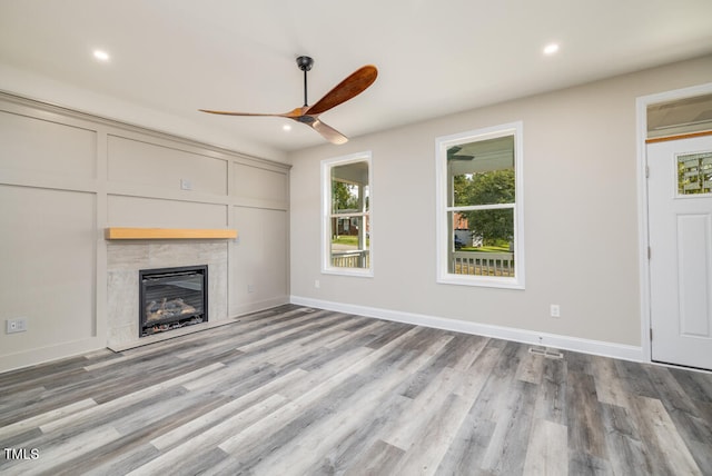 unfurnished living room featuring light wood-type flooring, a premium fireplace, and ceiling fan