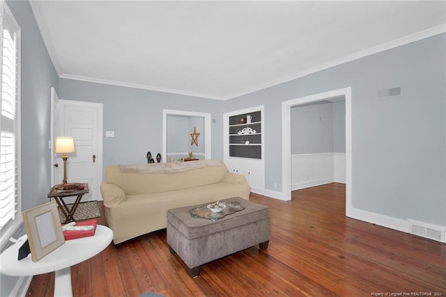 living room featuring built in features, dark hardwood / wood-style flooring, and a wealth of natural light