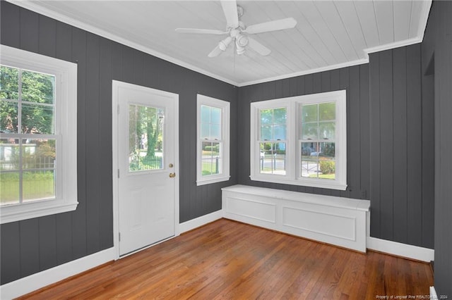 doorway to outside with ornamental molding, wood walls, ceiling fan, and hardwood / wood-style flooring