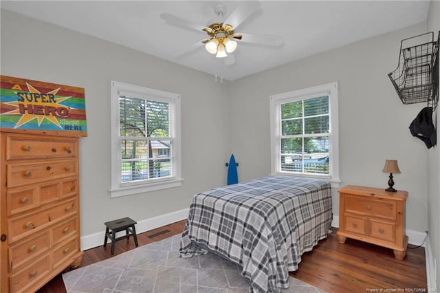 bedroom featuring multiple windows, dark hardwood / wood-style floors, and ceiling fan