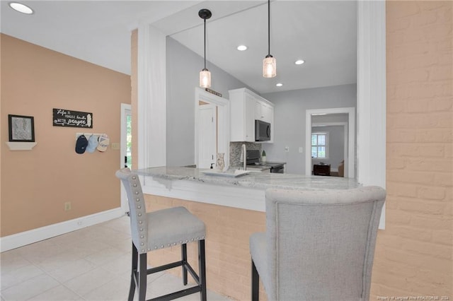 kitchen featuring white cabinetry, black range with electric stovetop, kitchen peninsula, a breakfast bar area, and pendant lighting