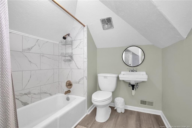 bathroom with toilet, hardwood / wood-style floors, a textured ceiling, and shower / bath combo