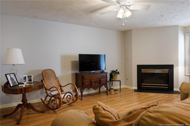 living room featuring hardwood / wood-style floors, a textured ceiling, and ceiling fan