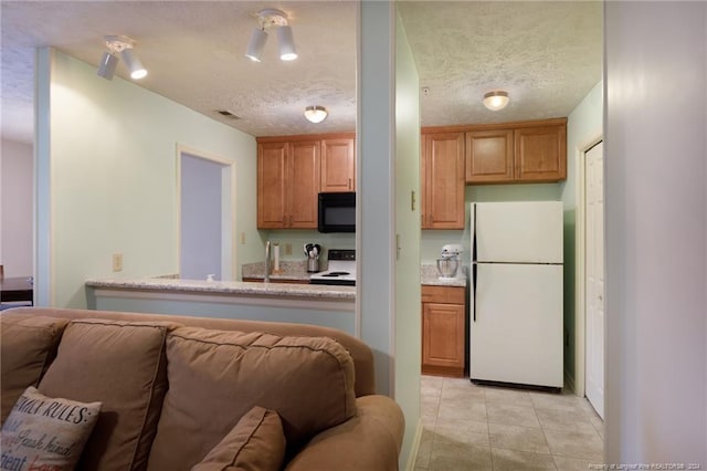 kitchen featuring white appliances, a textured ceiling, and light tile patterned floors