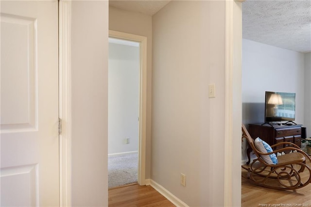 corridor featuring light hardwood / wood-style flooring and a textured ceiling