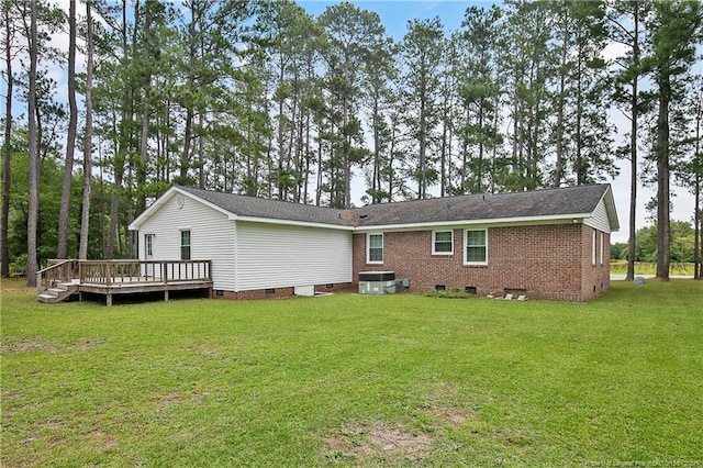 rear view of property featuring central AC unit, a deck, and a yard