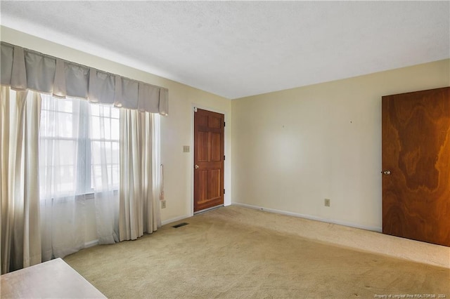 carpeted empty room with a textured ceiling