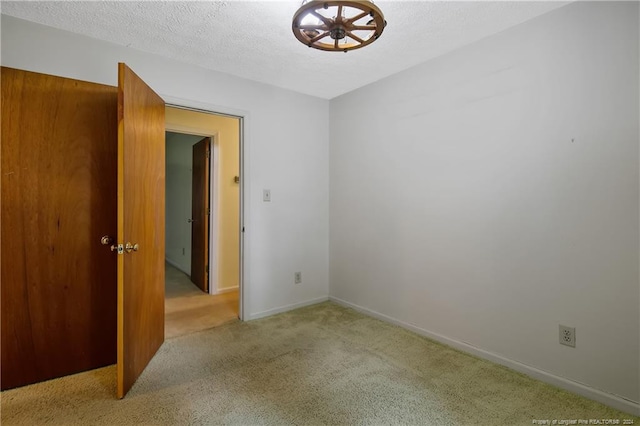 empty room featuring a textured ceiling and light colored carpet