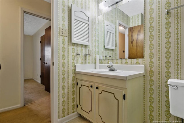 bathroom with a textured ceiling, vanity, and toilet