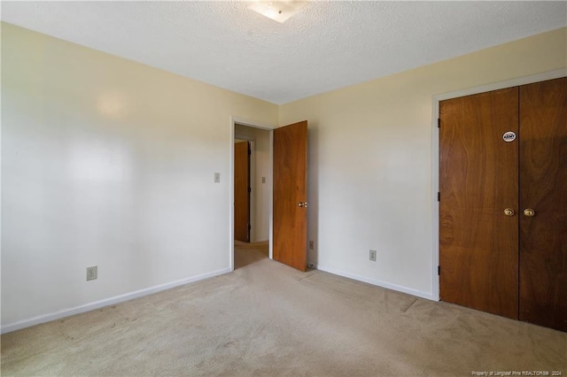 unfurnished bedroom with light carpet, a closet, and a textured ceiling