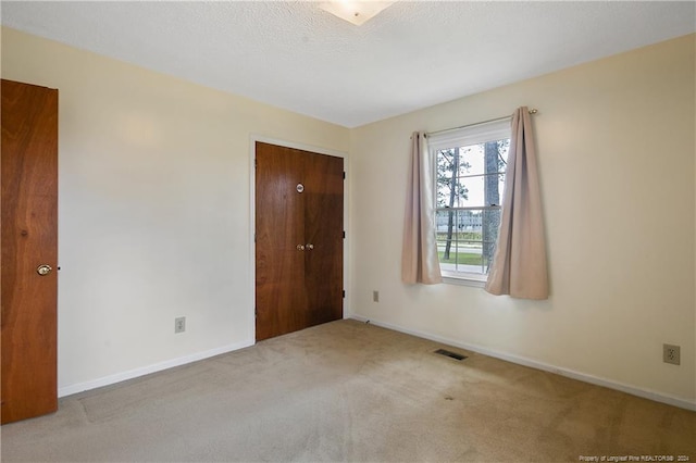 empty room with a textured ceiling and light colored carpet