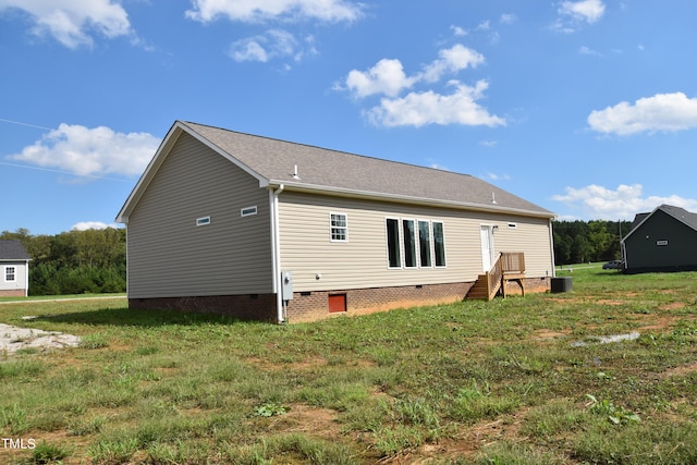 back of house with central AC unit and a yard