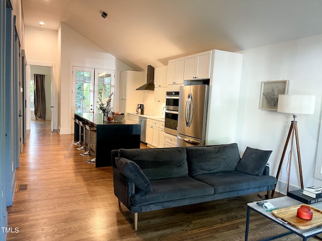 living room with high vaulted ceiling, french doors, and hardwood / wood-style flooring