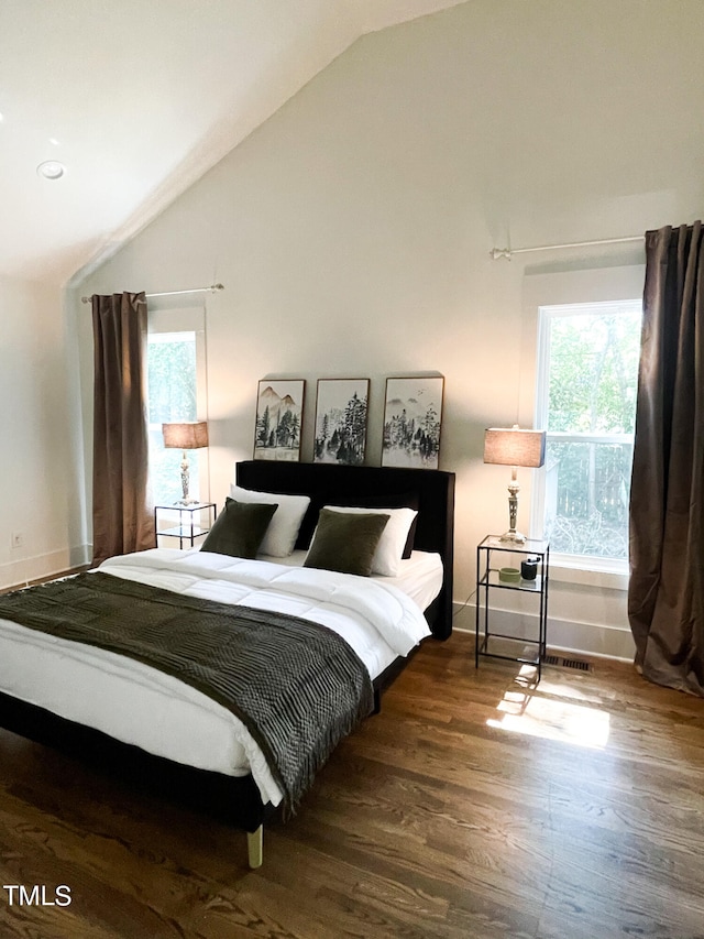 bedroom featuring dark hardwood / wood-style flooring, vaulted ceiling, and multiple windows