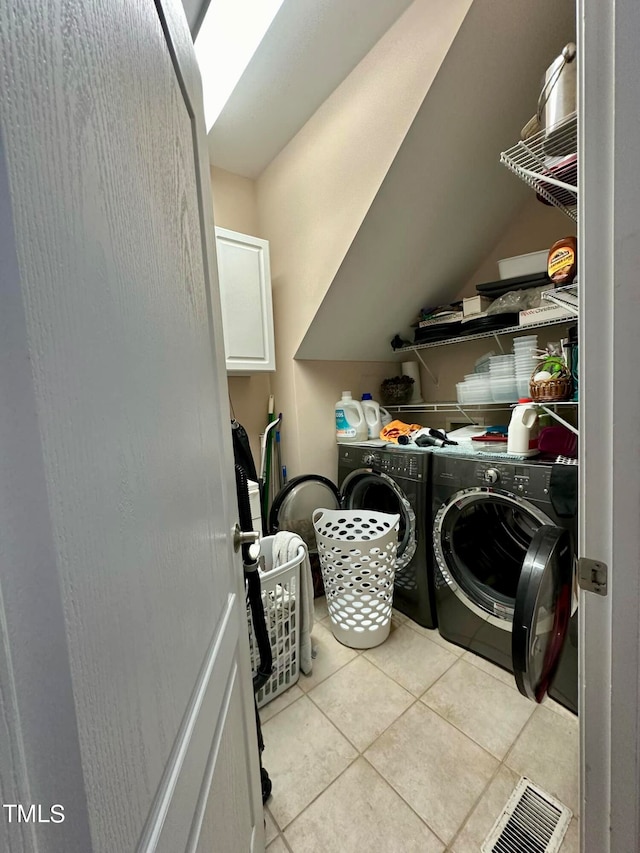 washroom featuring cabinets, light tile patterned floors, and washer and dryer